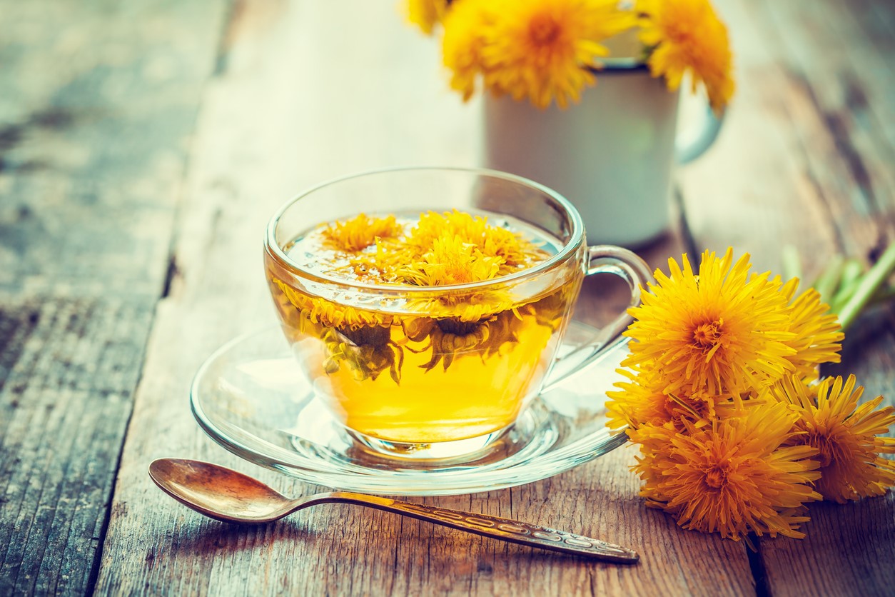 Cană de ceai de păpădie și flori aranjate pe o masă 