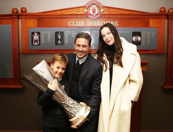Liv Tyler, Dave Gardner și fiul lor ținând un trofeu în mână, Manchester United
