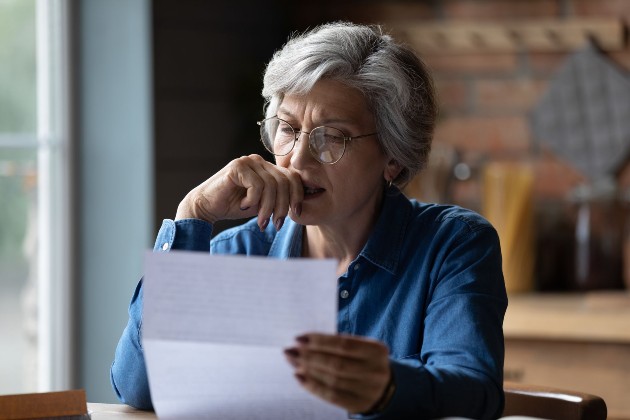 Imagine cu o femeie în vârstă care citește o scrisoare