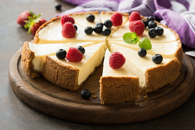 un cheesecake impartit in mai multe bucati si asezat pe un suport din lemn
