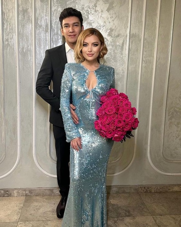 Elena Gheorghe într-o rochie albastră cu un buchet de flori în mână, alături de soțul ei Cornel Ene