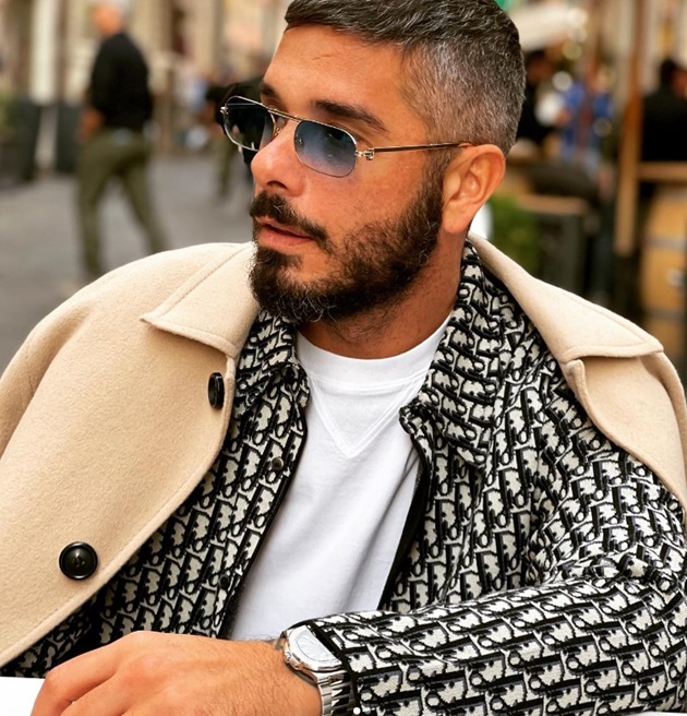 Vincenzo Castellano, pe terasa unui restaurant, îmbrăcat cu o haina Dior, palton și purtând ochelari de soare