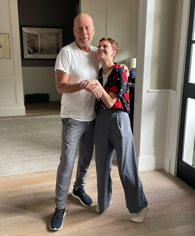 Tallulah și Bruce Willis tinându-se de mână și râzând, în casă
