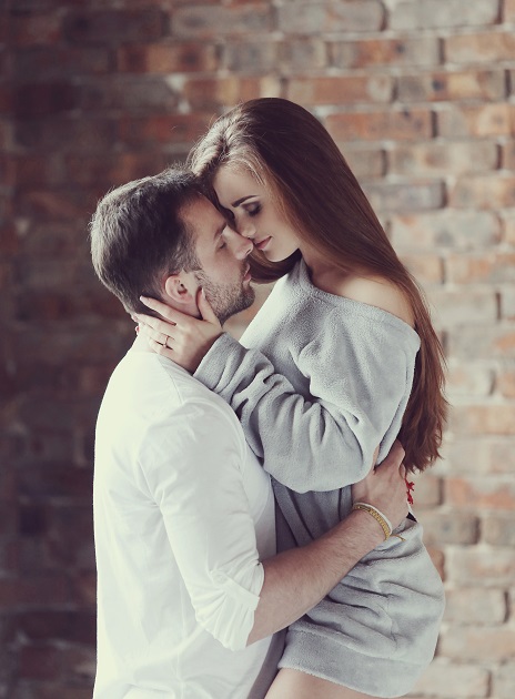 Cuplu de tineri care se privesc pasional în timp ce ea stă în brațele lui. 