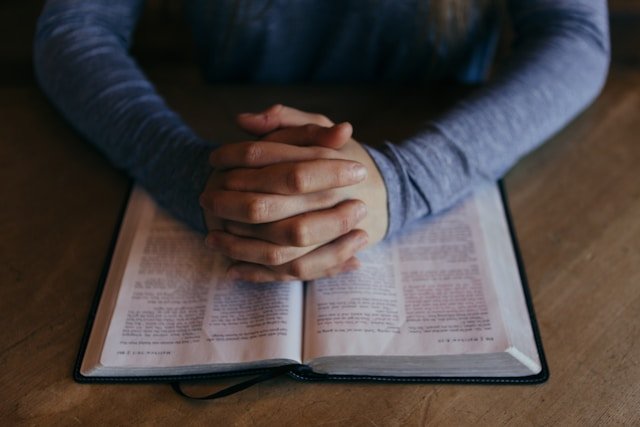 Persoană care se roagă cu Biblia