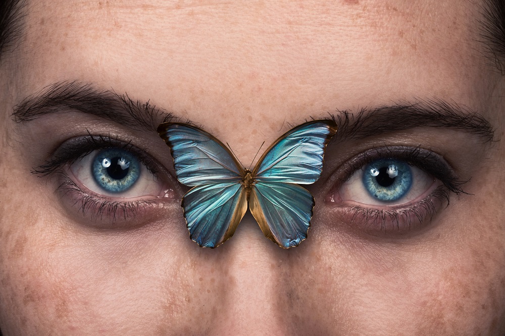 Ochi albaștri de femeie, cu un fluture albastru