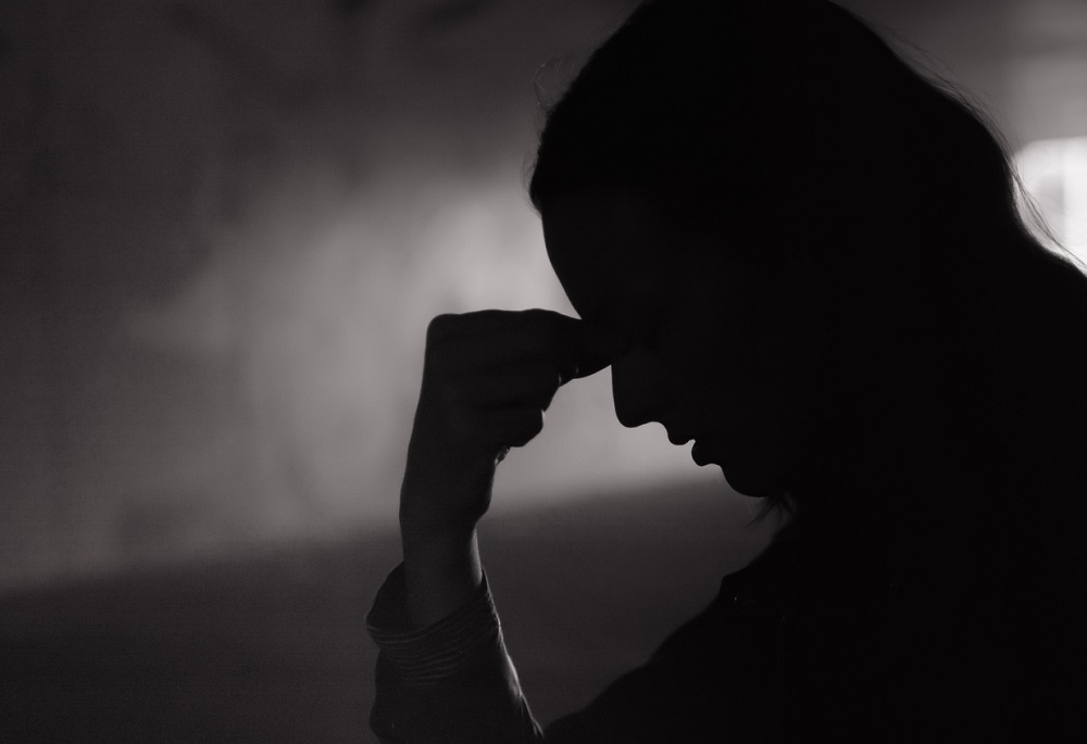 Femeie tristă, confuză și gânditoare, stând în întuneric