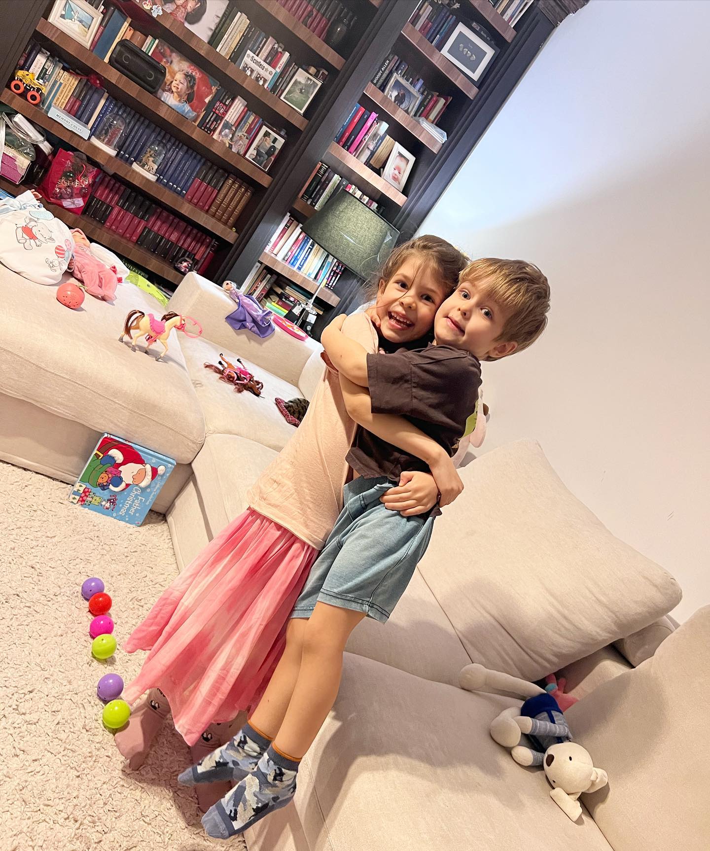 Ana și Vlad, copiii Simonei Gherghe, jucându-se împreună într-o sufragerie plină cu jucării și cărți