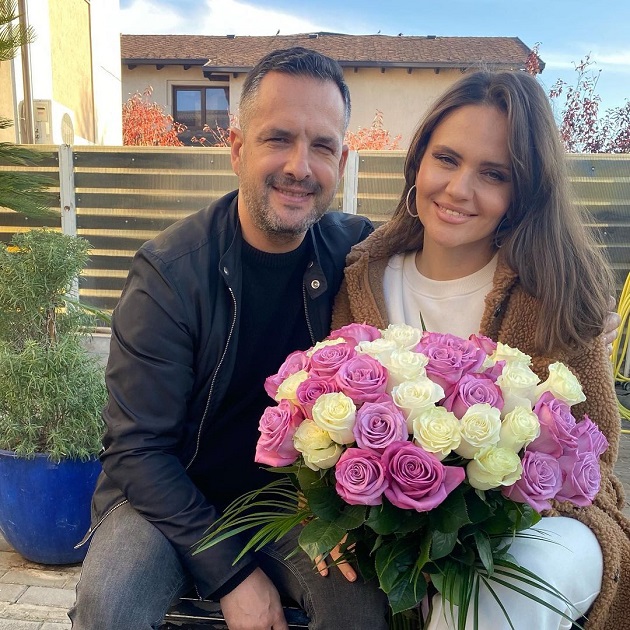 Mădălin Ionescu și Cristina Șișcanu în curtea casei lor, în timp ce ea ține în brațe un buchet de trandafiri
