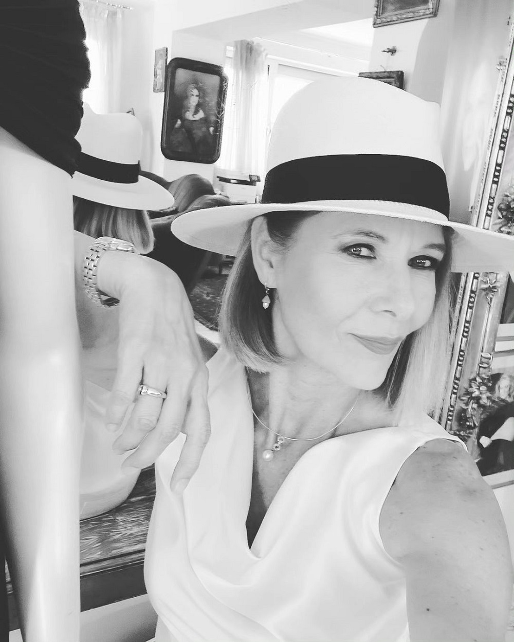 Selfie cu Romanița Iovan îmbrăcată în alb, în timp ce poartă o pălărie și stă cu spatele la oglindă.