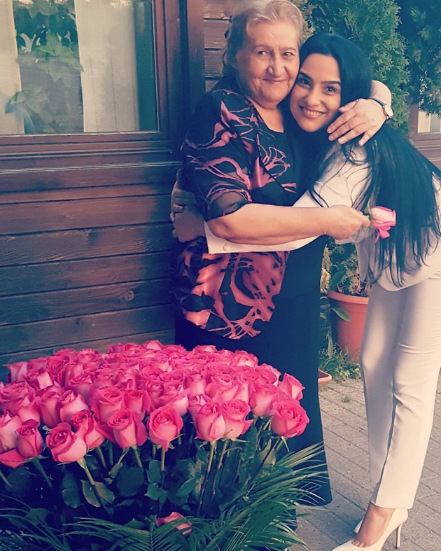Gabi Luncă îmbrățișată de fiica sa, Rebeca Onoriu, lângă un buchet uriaș de trandafiri roz