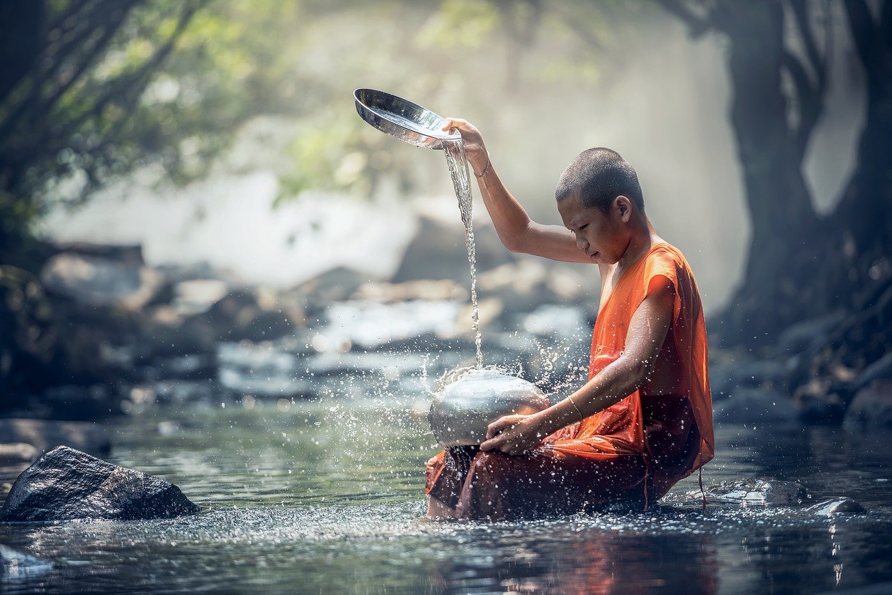 tănar budist aflat într-o apă mare, umple un recipient cu apa sau exercitat un ritual legat de apă