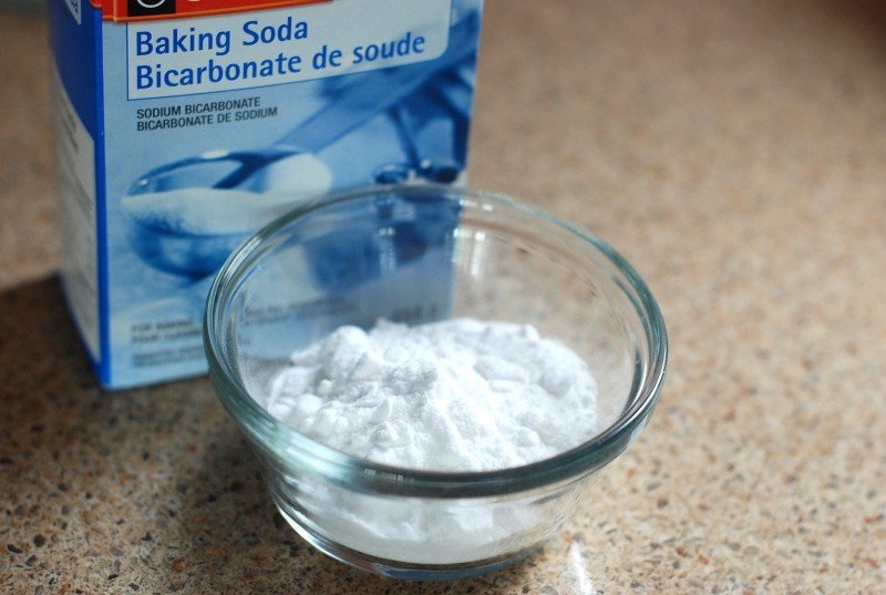 cutie albastra pe care scrie baking soda si pudra de bicarbonat de sodiu langa cutie pe masa intr-un bol