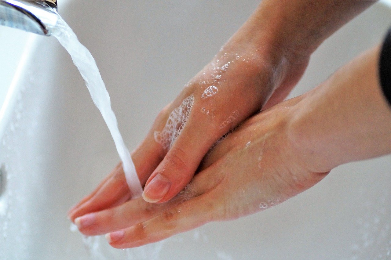 maini de femeie care se spala cu apa si sapun la chiuveta