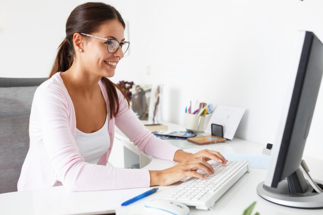 femeie cu ochelari scriind la calculator