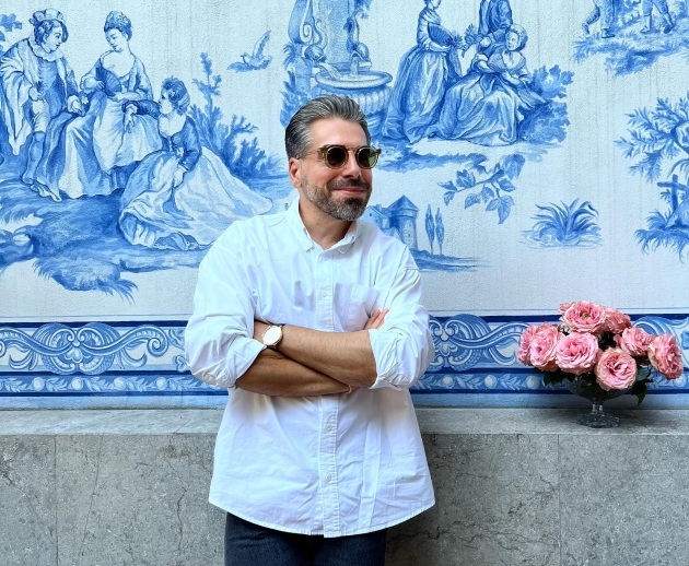 maurice munteanu imbracat lejer cu o camasa pozeaza in aer liber langa un buchet de trandafiri