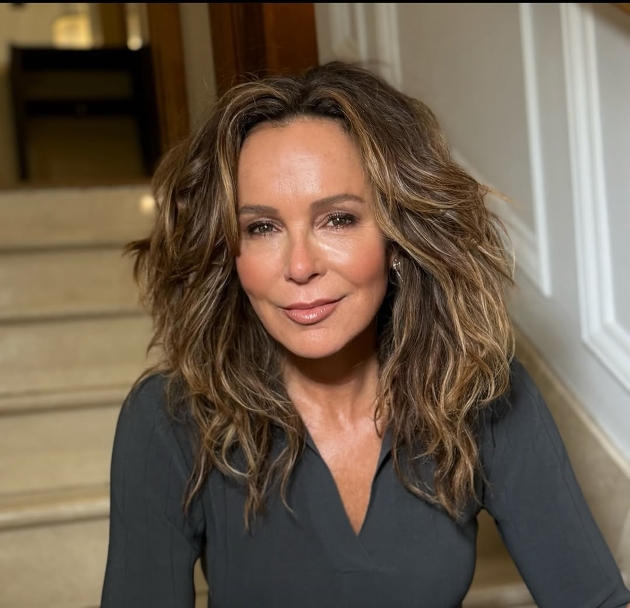 jennifer grey pozeaza pe scari, coafata si imbracata pentru un eveniment