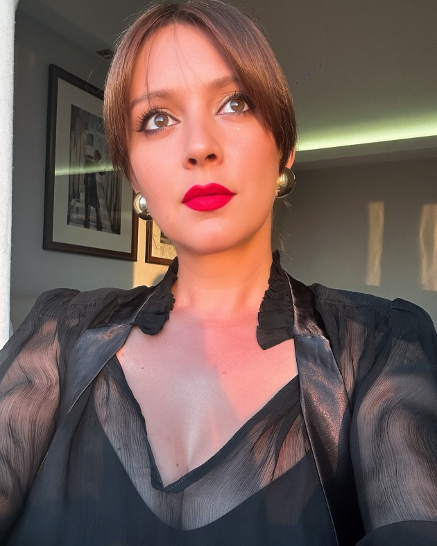 diana dumitrescu cu ruj rosu si o rochie neagra se uita in departare