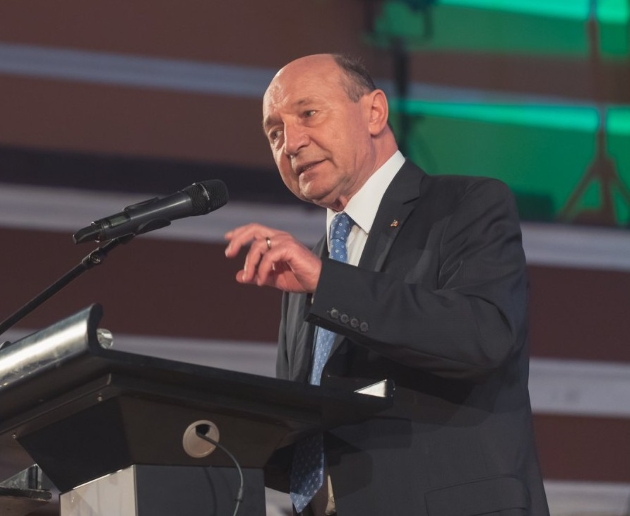traian basescu vorbeste la microfon imbracat in costum negru si camasa alba