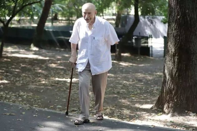 victor rebengiuc la plimbare in parcul cismigiu cu baston imbracat cu camasa alba si pantaloni bej