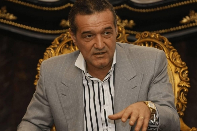 gigi becali imbracat in costum gri sta pe un scaun auriu