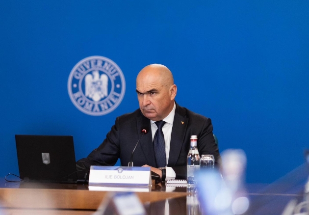 ilie bolojan imbracat cu costum negru expresie serioasa in timpul unei sedinte de guvern