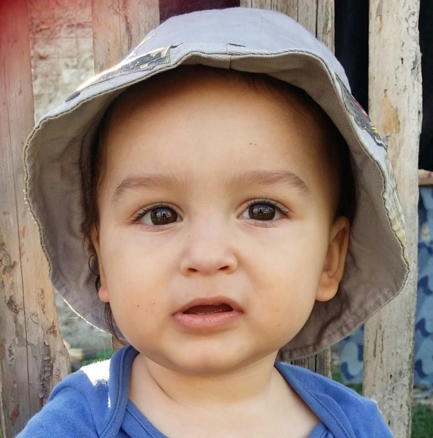 copil cu ochi negri si palarie pe cap care se uita la camera
