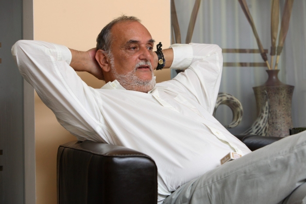 dinu patriciu cu o camasa alba intins cu mainile im spatele capului