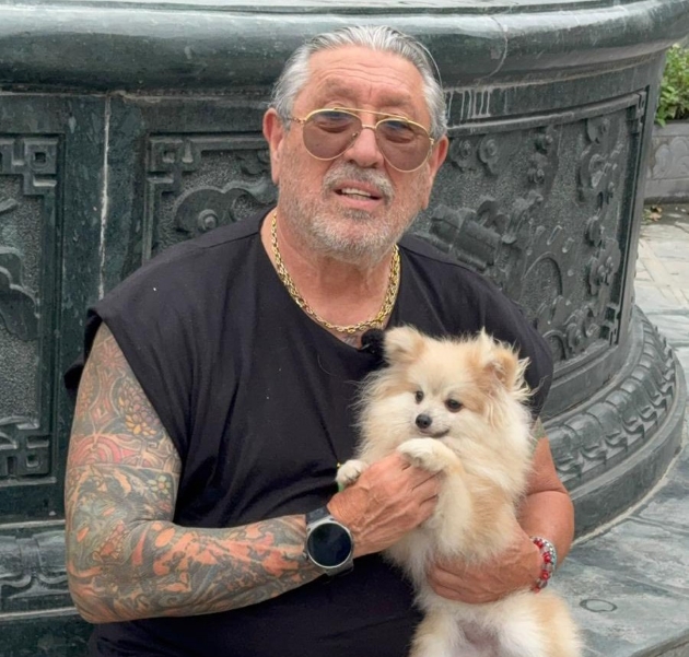 serghei mizil imbracat cu un tricou negru tine in brate un caine pomeranian