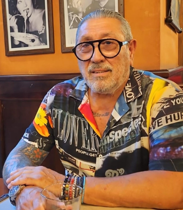 serghei mizil sta la masa imbracat cu o camasa colorata