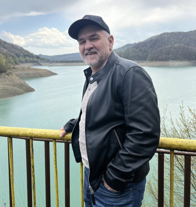 leonard doroftei pe un pod sprijinit de balustrada zambitor imbracat lejer