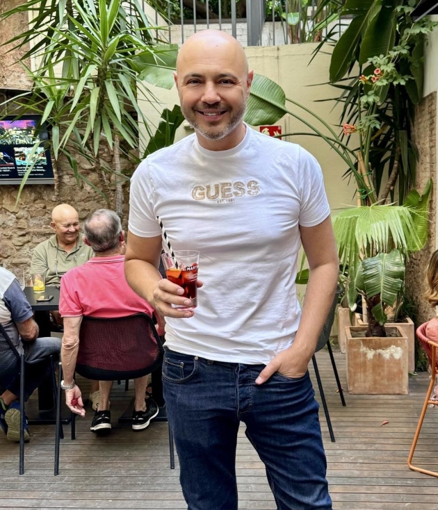 mihai mitoseru cu un tricou alb si blugi tine un cocktail in mana