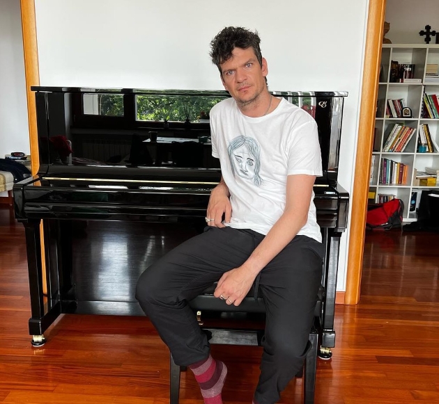 tudor chirila imbracat in tricou alb pozeaza acasa in fata pianului