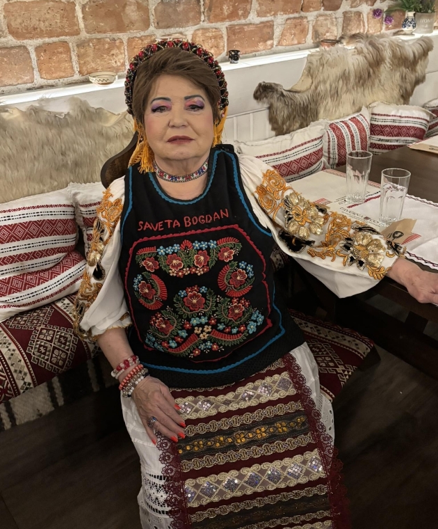 saveta bogdan imbracata in costum popular sta la masa in timpul unui eveniment