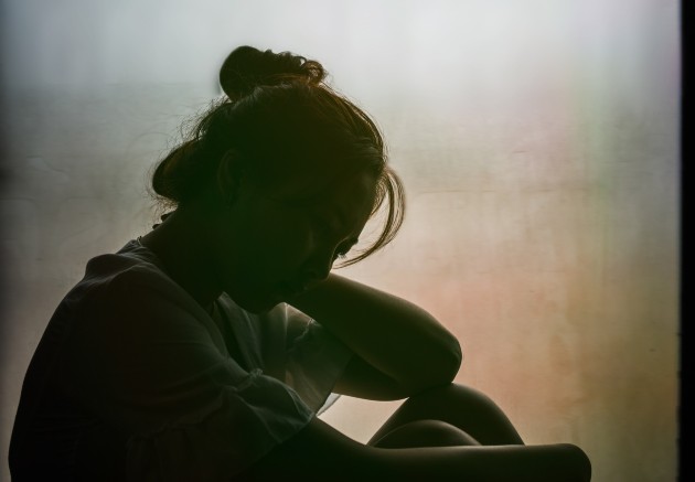 Fotografie cu o femeie tristă care stă la geam