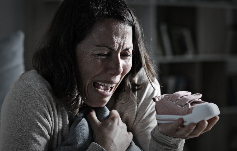 Imagine cu o femeie care plânge pentru că și-a pierdut copilul