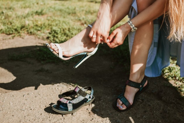Imagine cu o picioarele unei femei care schimbă sandalele cu tocuri