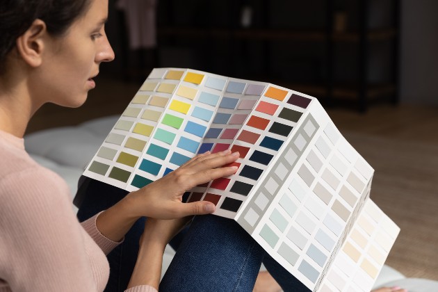 Imagine cu o femeie care se uită peste un catalog cu culori