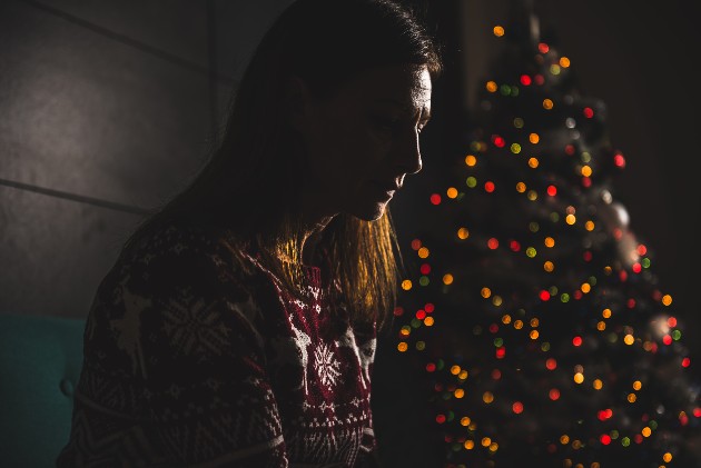 Imagine cu o femeie tristă lângă un brad de Crăciun