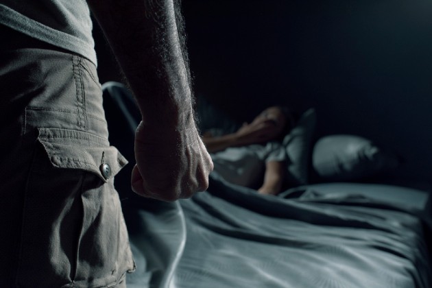 Imagine cu o mână de bărbat și cu o femeie care se ascunde în pat
