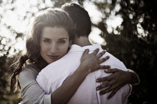 Fotografie cu o femeie care îmbrățișează un bărbat care stă cu spatele