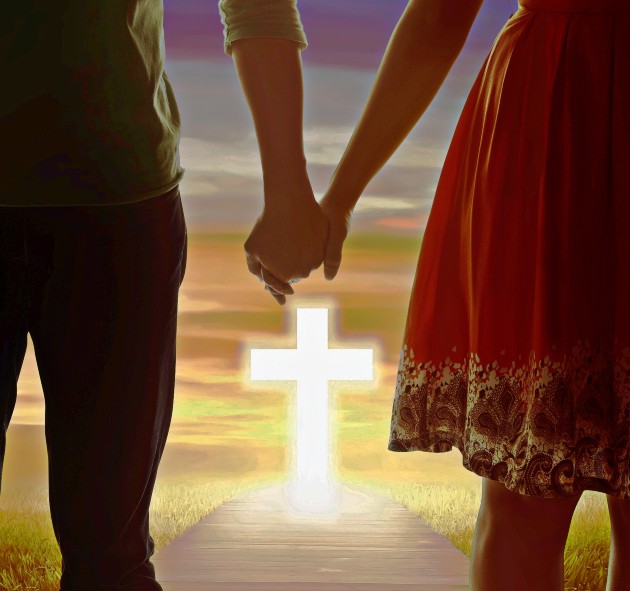 Imagine cu un bărbat și o femeie care se țin de mână și o cruce între ei doi