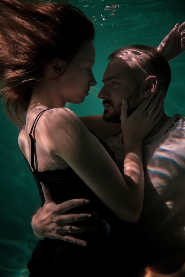 Imagine cu un bărbat și o femeie care se îmbrățișează sub apă