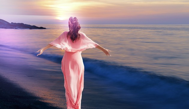 Imagine cu o femeie în rochie roz care merge pe malul mării