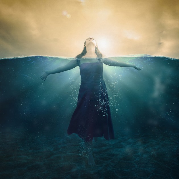 Imagine cu o femeie îmbrăcată în rochie care stă în apă