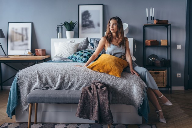 Imagine cu o femeie care stă pe pat în dormitor