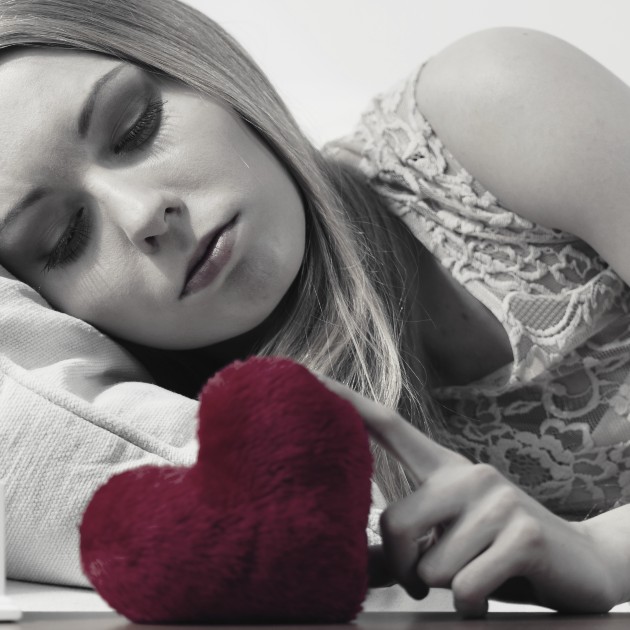 Imagine cu o femeie tristă care se uită la o inimă roșie