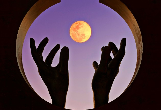 Imagine cu două mâini în jurul lunii