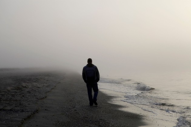 Imagine cu un bărbat care se plimbă singur pe plajă