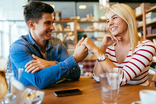 Imagine cu un bărbat și o femeie care zâmbesc unul la celălalt într-un restaurant